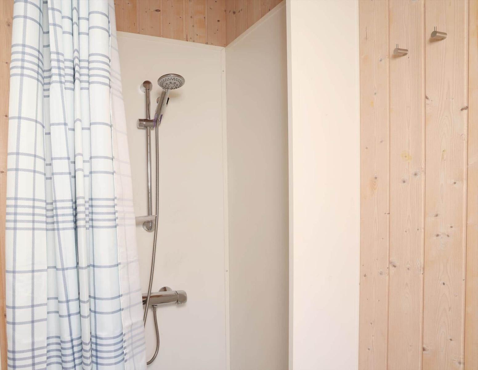 Dusche mit Duschvorhang und Handbrause in Holzbadezimmer