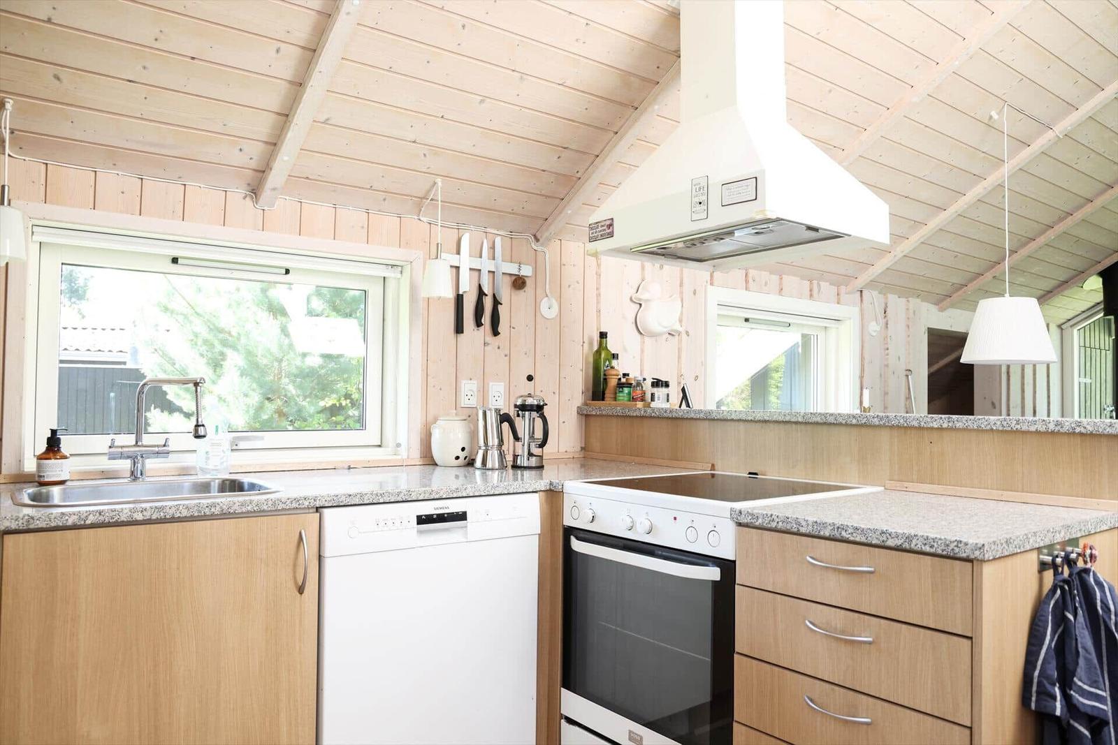 Küche mit Holzwand, Spüle, Herd und Dunstabzug.