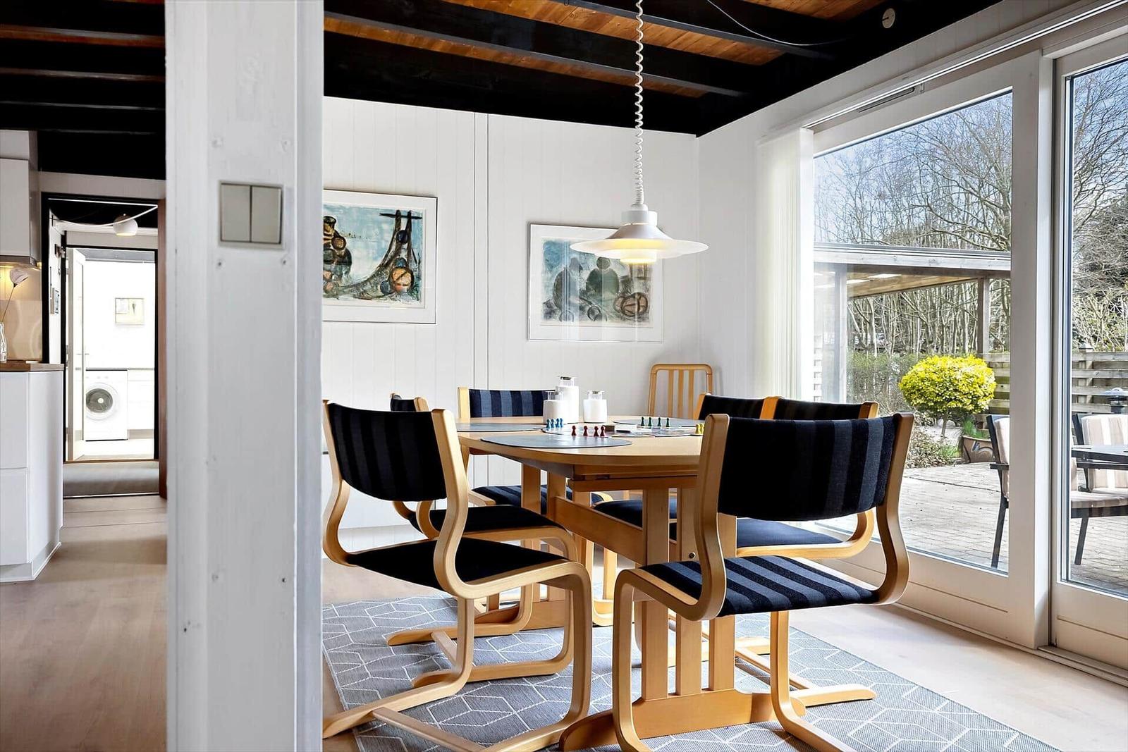 Esszimmer mit Holztisch, Stühlen und Fensterblick auf Garten