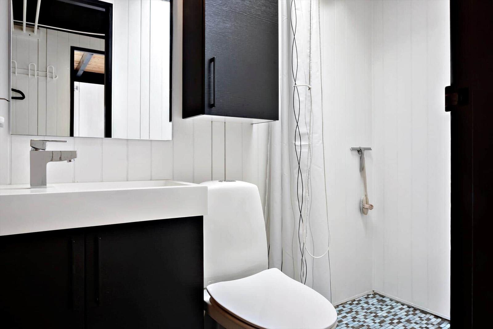 Bad mit Waschbecken, Toilette und Dusche mit Mosaikboden.