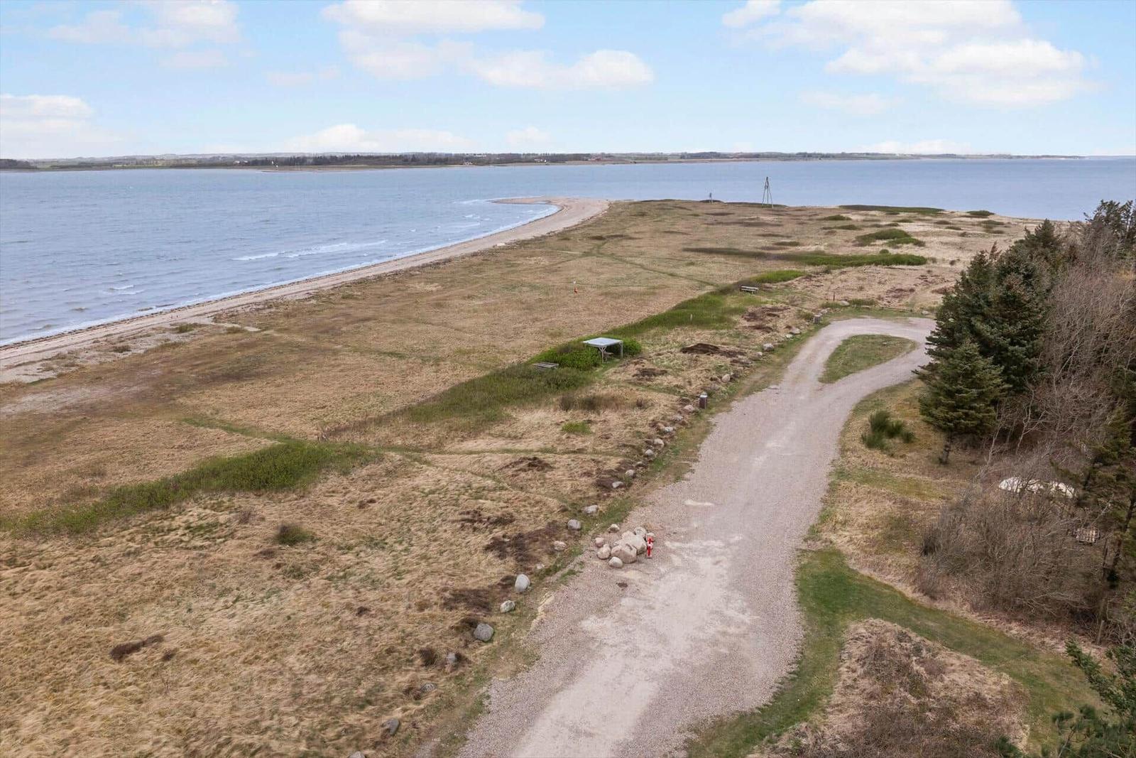 Grasland mit Steigweg und Strand. Blick auf Wasser und Horizont.