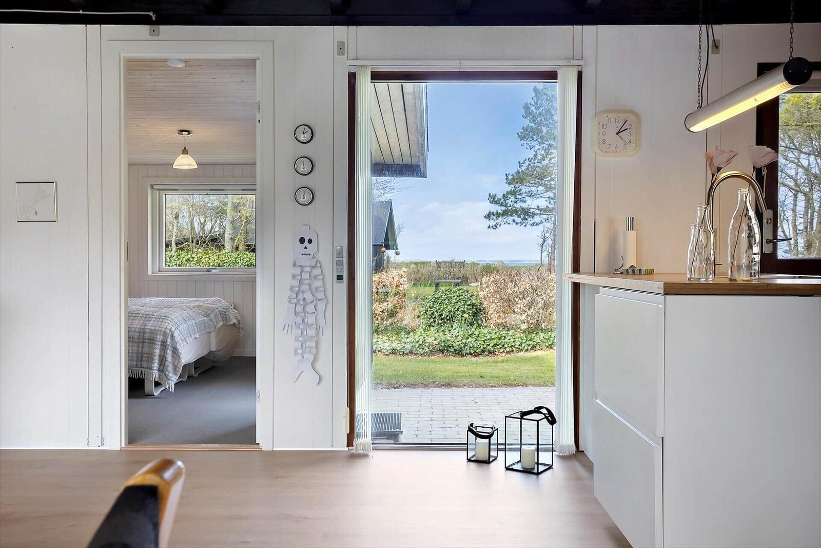 Wohnbereich mit Blick auf Garten, Schlafzimmer und Küchenzeile mit Holzoberfläche.