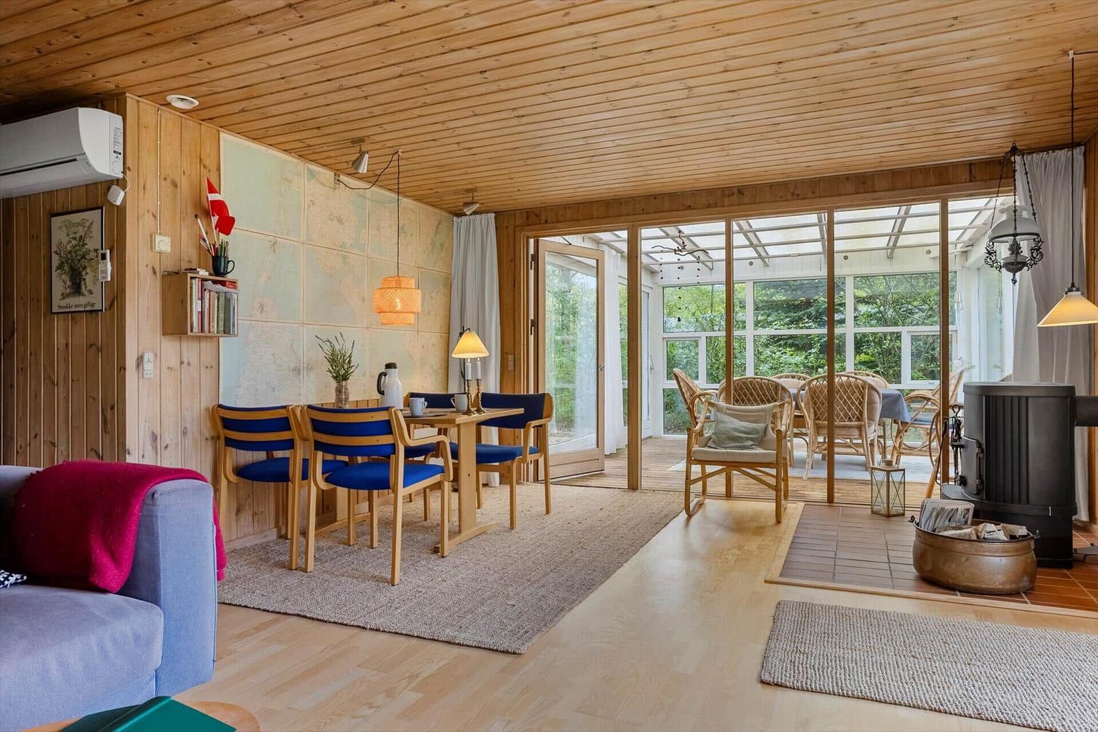 Wohnraum mit Essbereich, Holzdecke und Blick auf Terrasse.