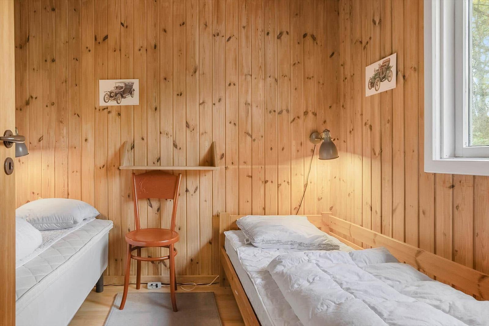 Zwei Betten in einem Raum mit Holzwandverkleidung und Fenster.