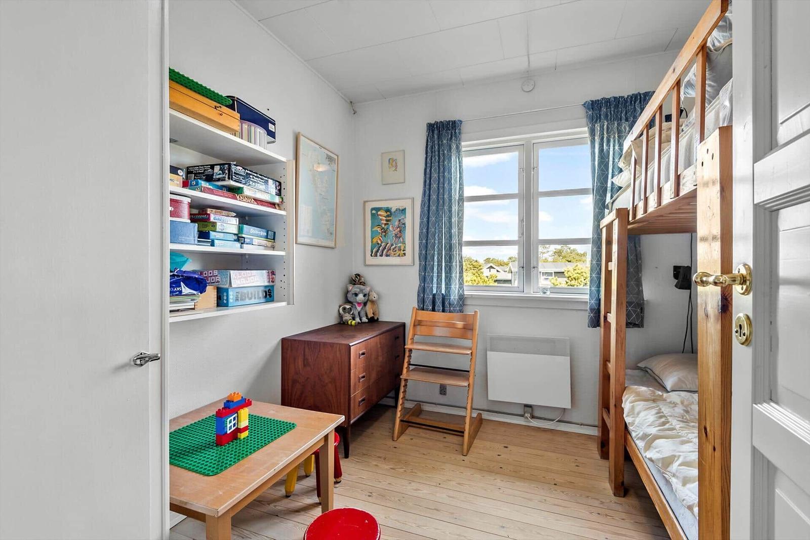 Ein Kinderzimmer mit Doppelstockbett, Schreibtisch und Spielzeugregal.