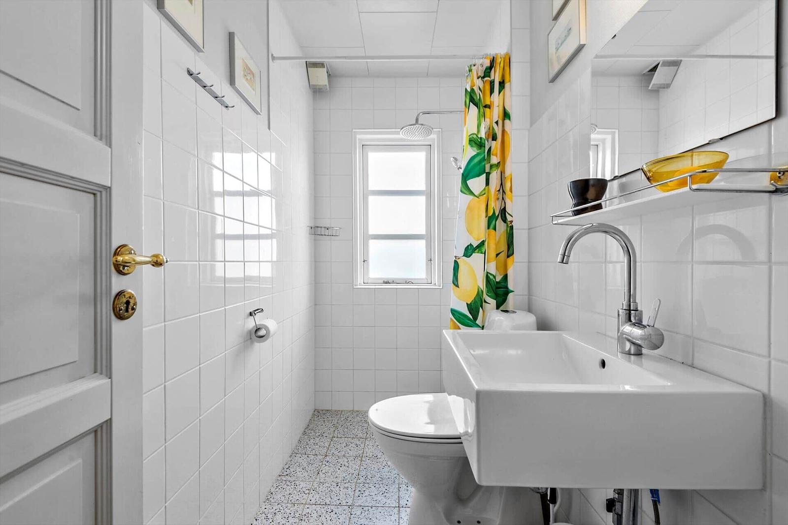 Badezimmer mit Dusche, Waschbecken und Toilette. Gelb-grüner Duschvorhang.