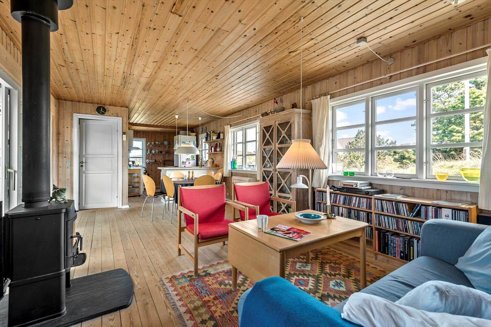 Wohnzimmer mit Holzdecke, Kamin und Blick auf die Landschaft.