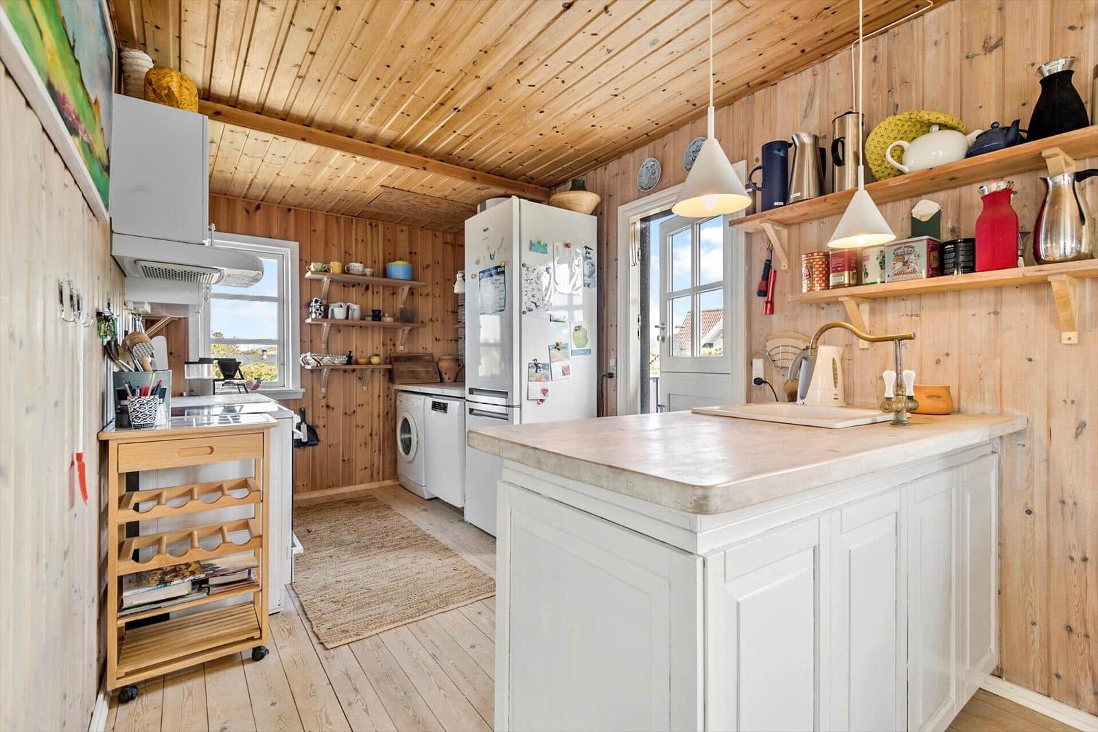 Küche mit Holzwand, weißer Insel und Küchengeräten.