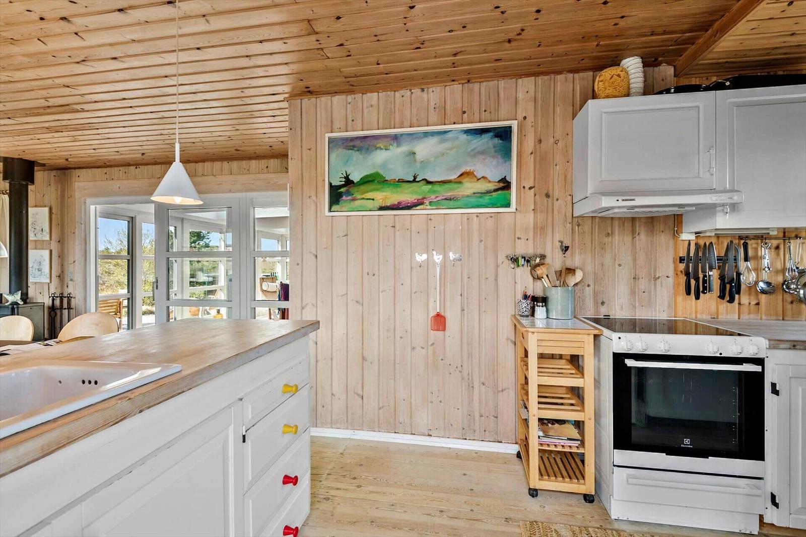 Küche mit Holzwänden, weißer Arbeitsplatte und Kochgeräten.