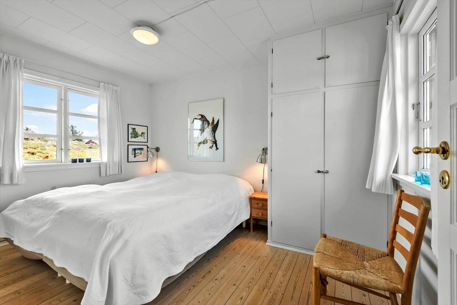 Schlafzimmer mit Bett, Kleiderschrank und Fenster mit Aussicht.
