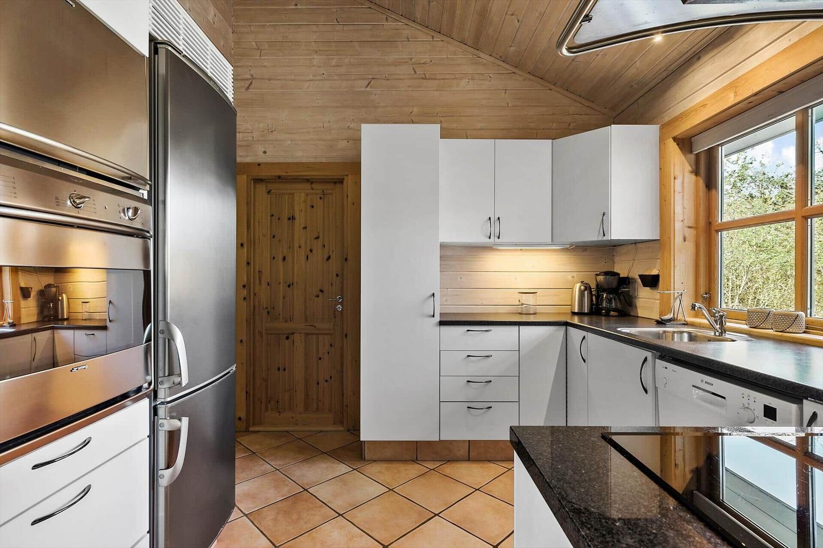 Küche mit weißen Schränken, Edelstahlgeräten und Holzdecke.