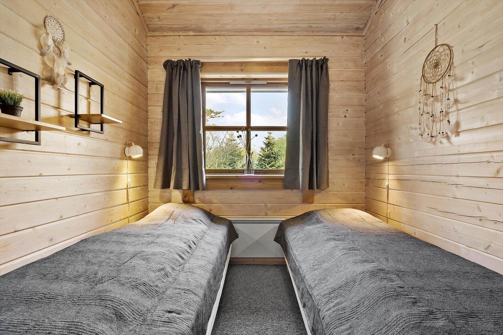 Zwei Betten in einem Holzraum mit Fenster und Vorhängen.