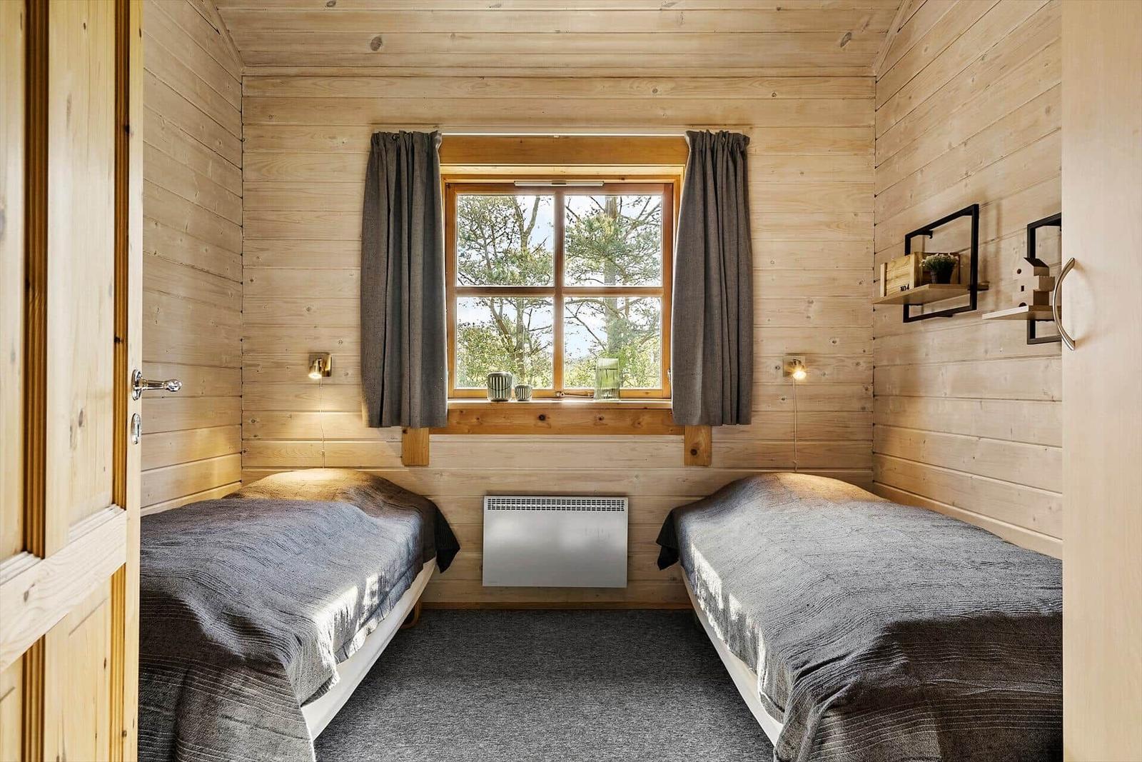 Zwei Betten in einem Holzraum mit Fenster und Heizung.