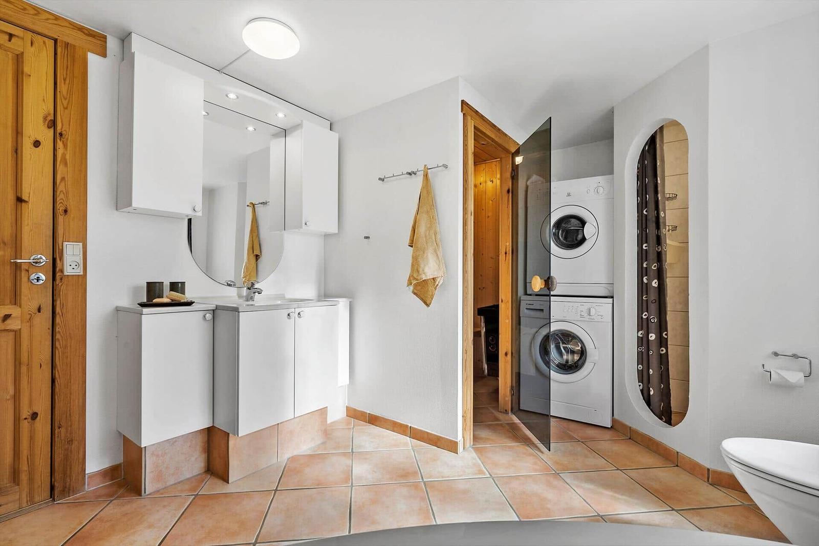 Badezimmer mit Waschmaschine, Spiegel und Toilette.