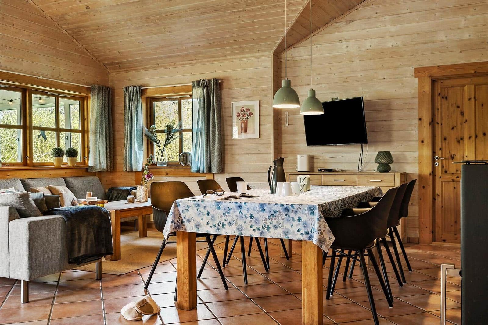 Wohn- und Essbereich mit Holzwänden, Tisch mit Tischdecke und Sofa.