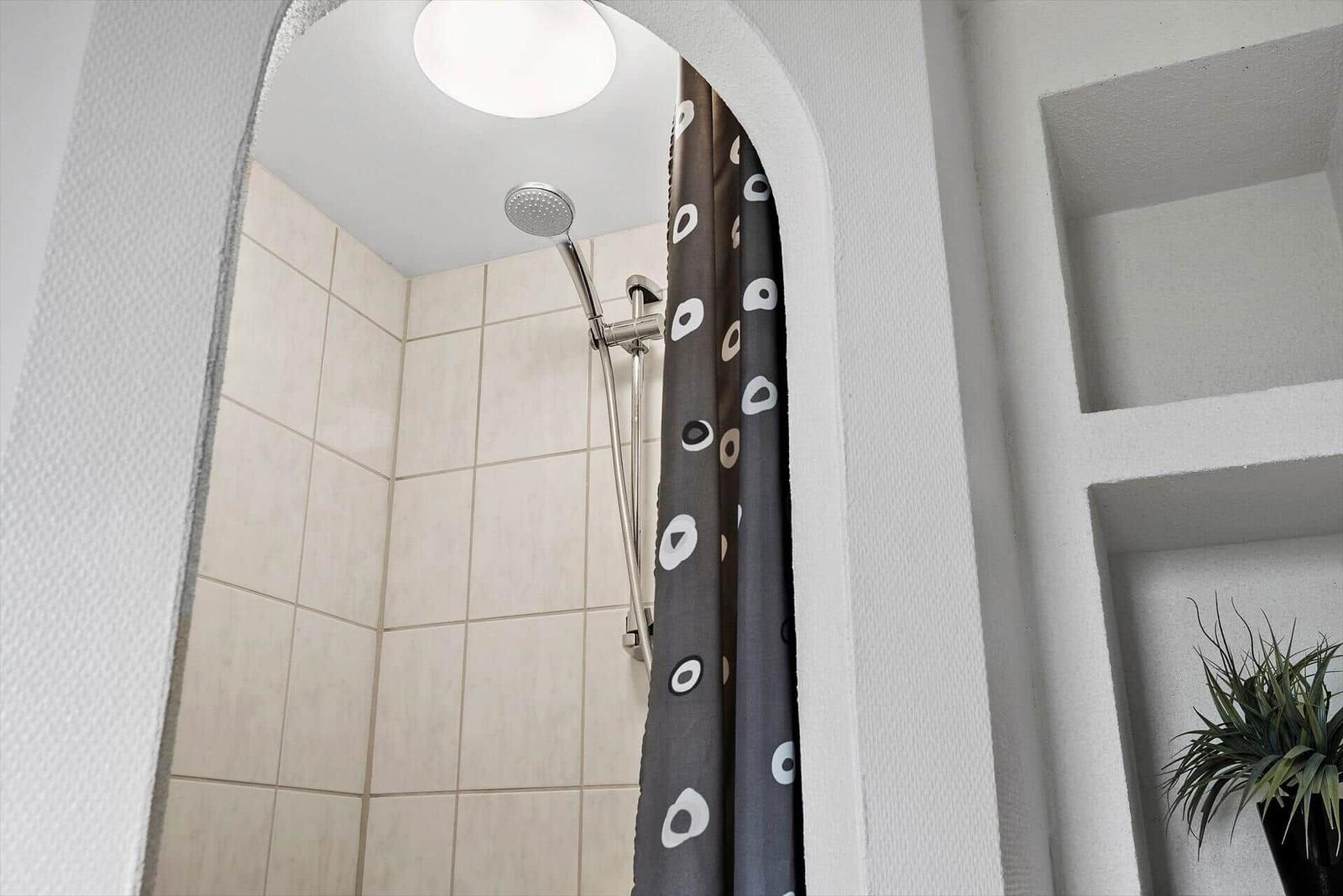 Dusche mit Duschvorhang und Duschkopf in Bad