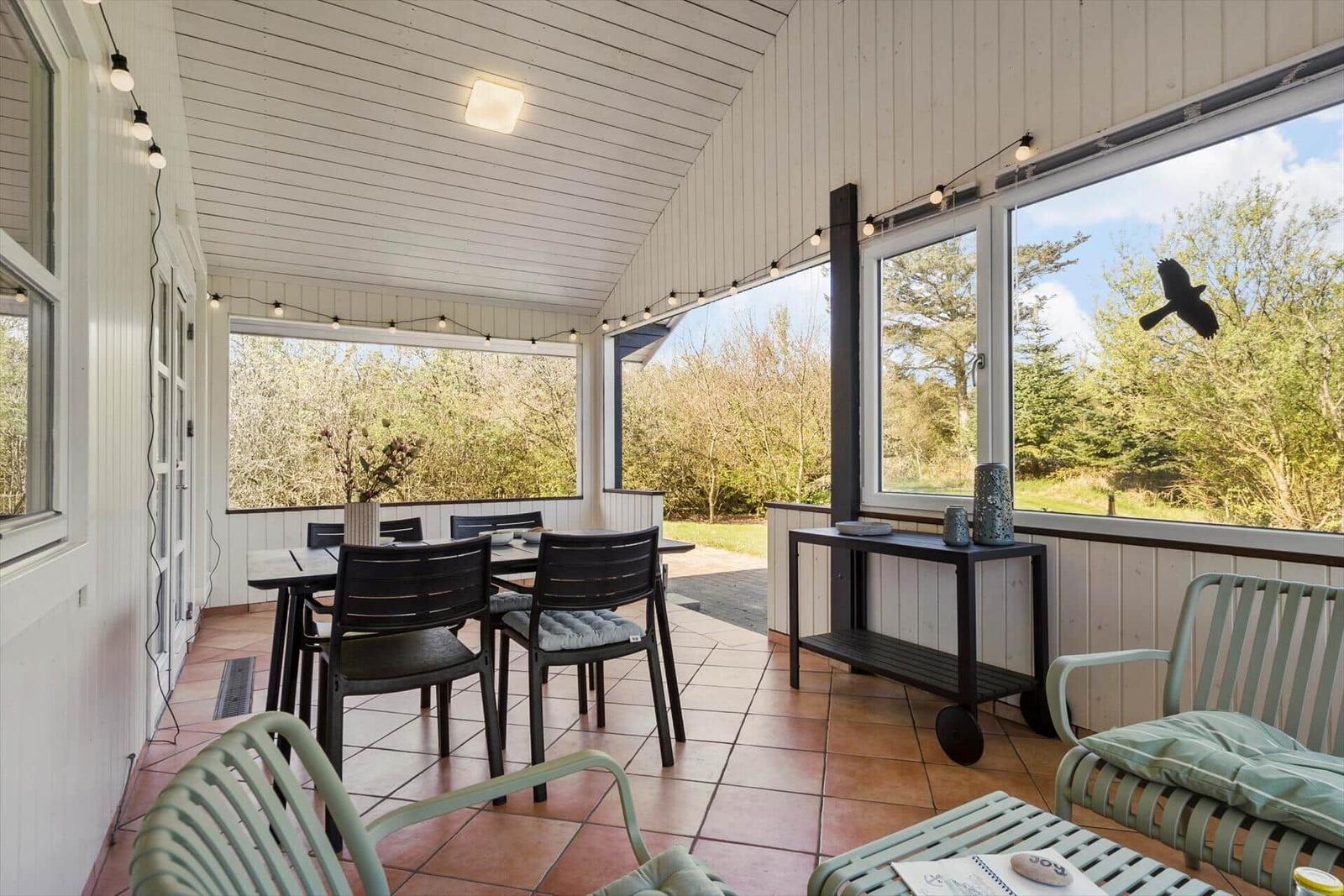 Terrasse mit Tisch, Stühlen und Blick auf grüne Landschaft.