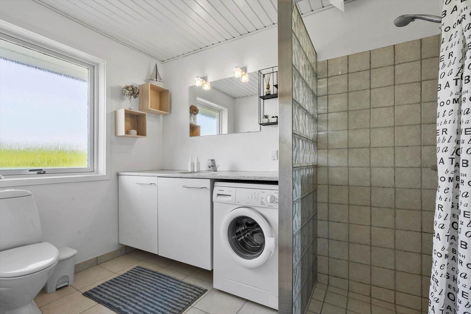 Badezimmer mit Waschmaschine, Dusche und Fenster