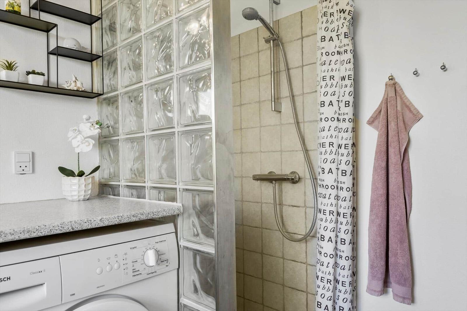 Badezimmer mit Dusche, Waschmaschine und Glasblöcken an der Wand.