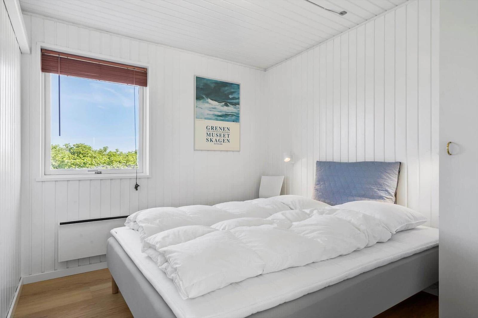 Schlafzimmer mit Bett, Fenster und Wandbild.
