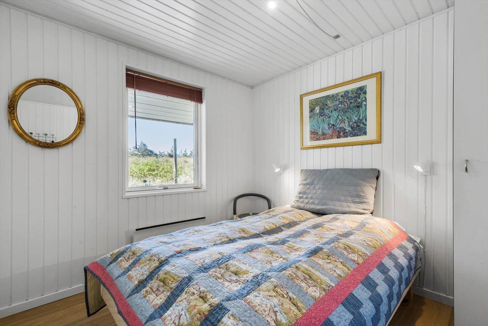 Schlafzimmer mit Bett, Fenster, Spiegel und Wandbild.