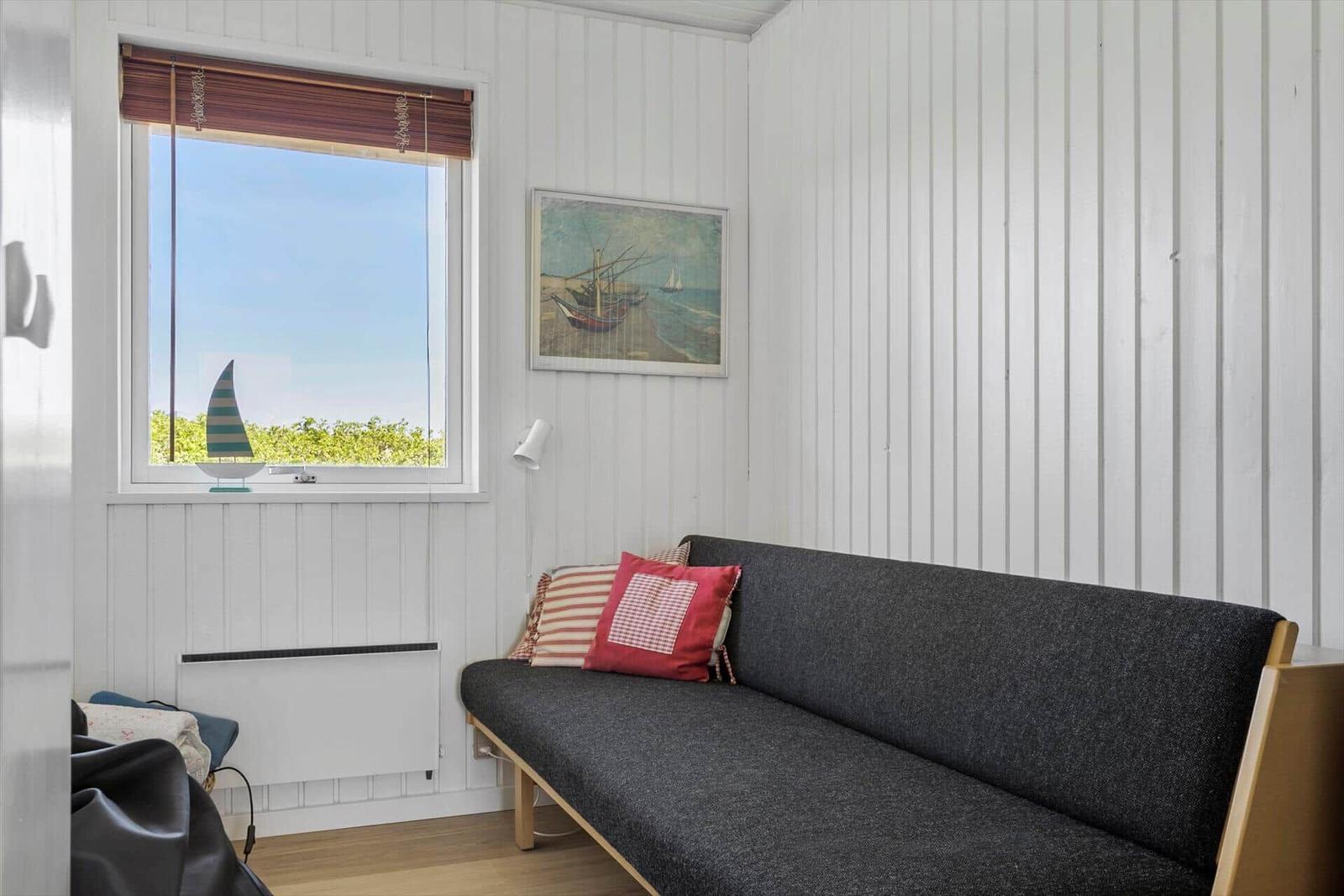 Ein Wohnraum mit Sofa, Fenster und Wandbild.