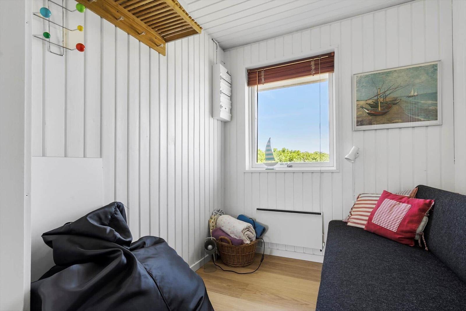 Ein Raum mit Sofa, Fenster und Wandbild. Holzfußboden und weiße Wände.