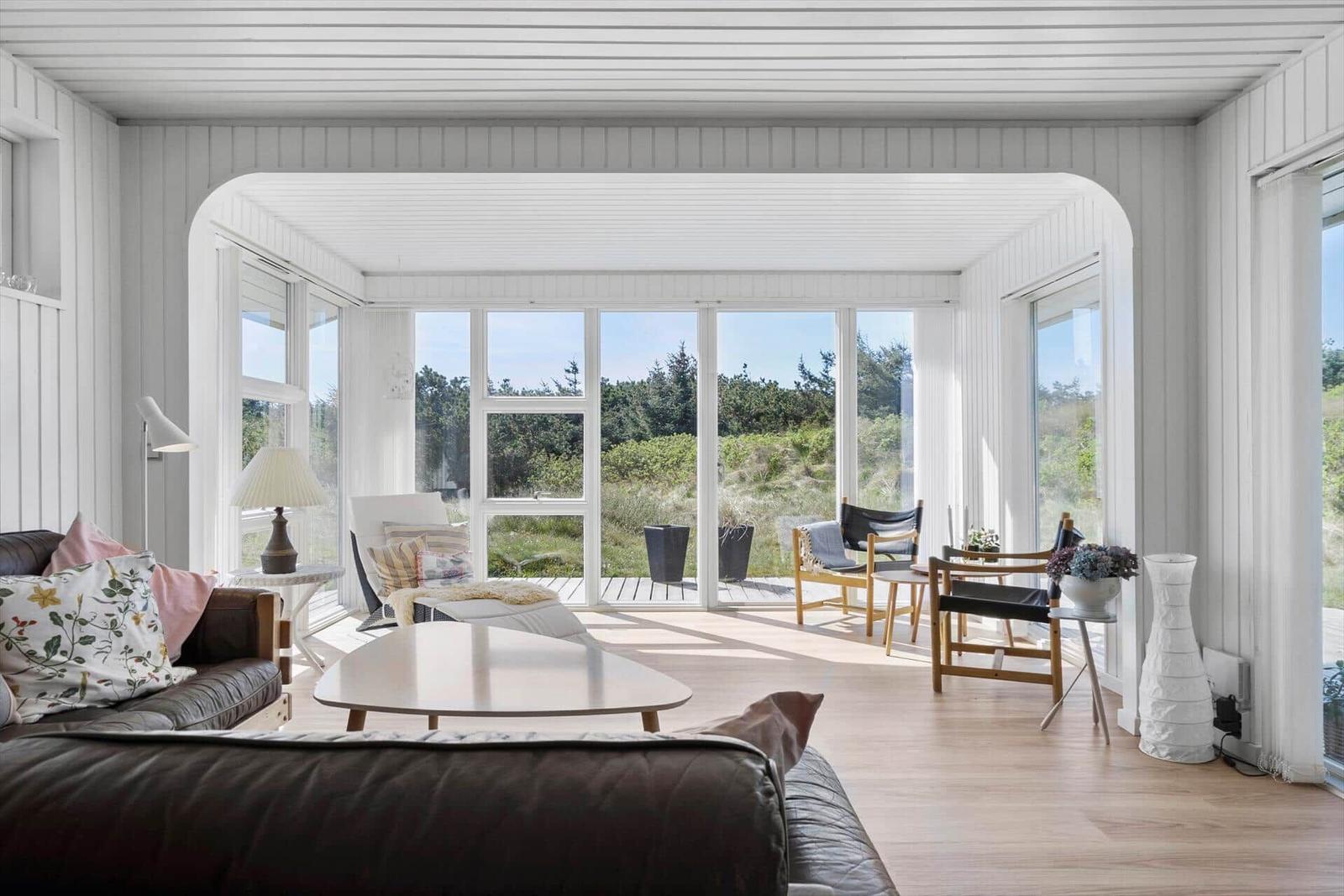 Wohnraum mit großem Fensterblick auf Grünland und Bäume.