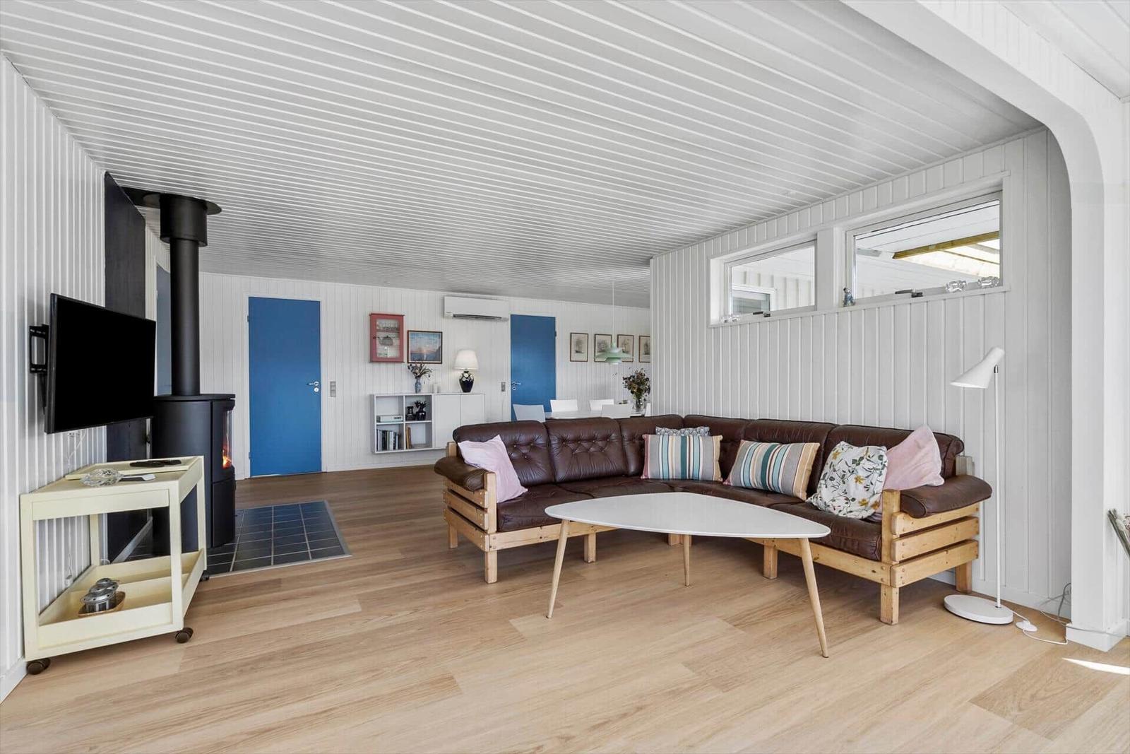 Wohnzimmer mit braunem Sofa, Holzboden und weißem Deckenpaneel.