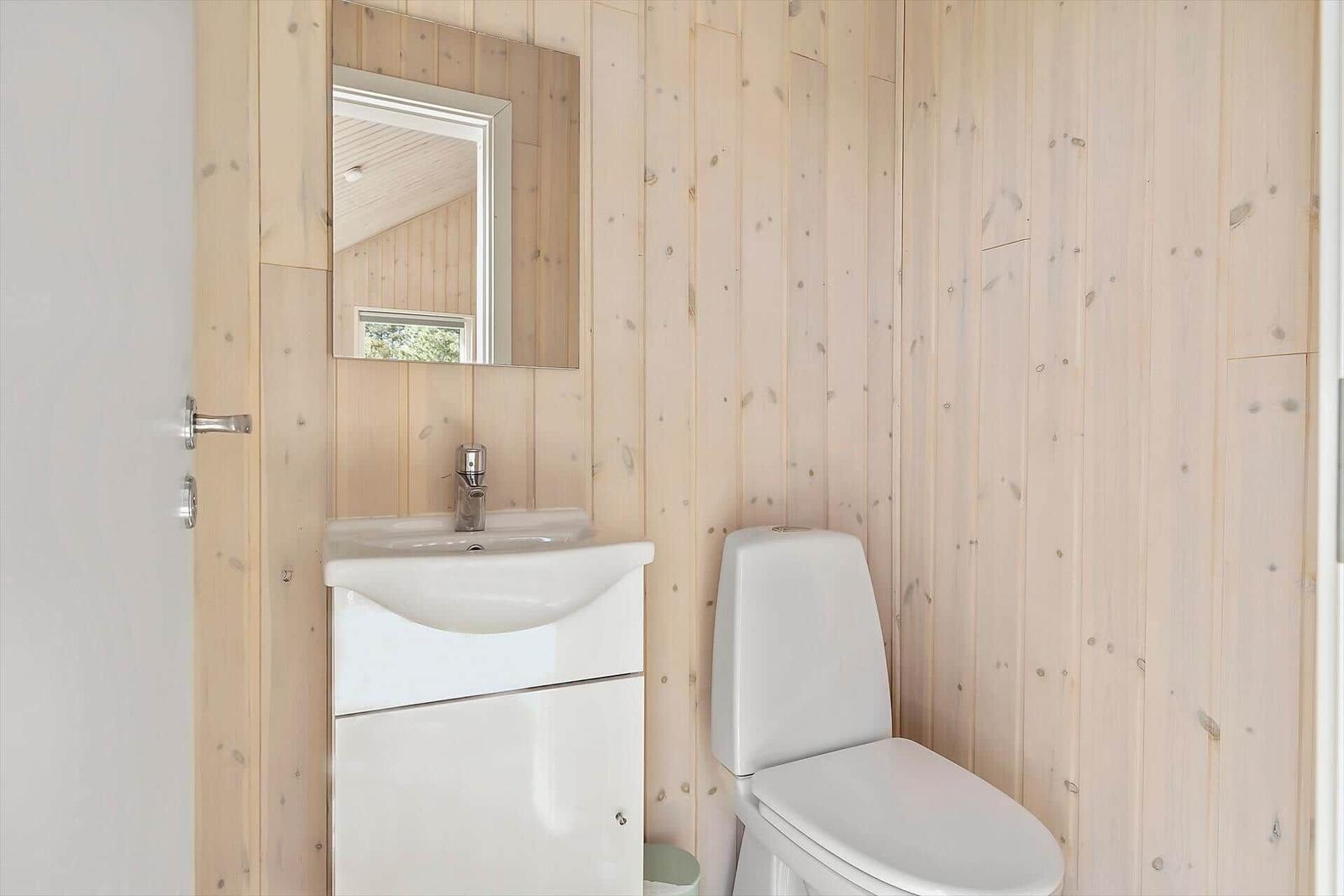 Badezimmer mit Toilette und Waschbecken an Holzwand
