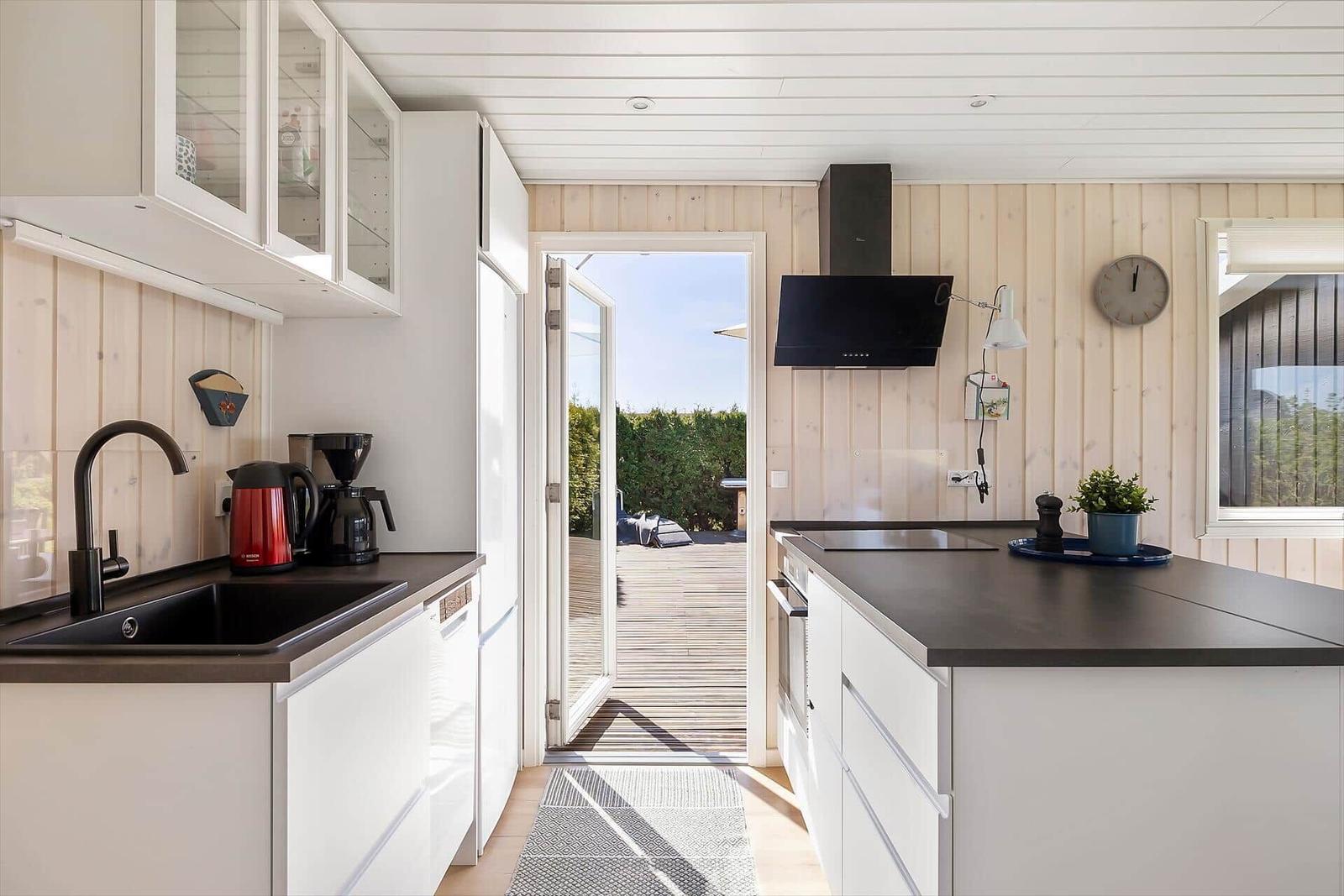 Küche mit weißen Schränken, schwarzer Arbeitsplatte und Blick auf die Terrasse.