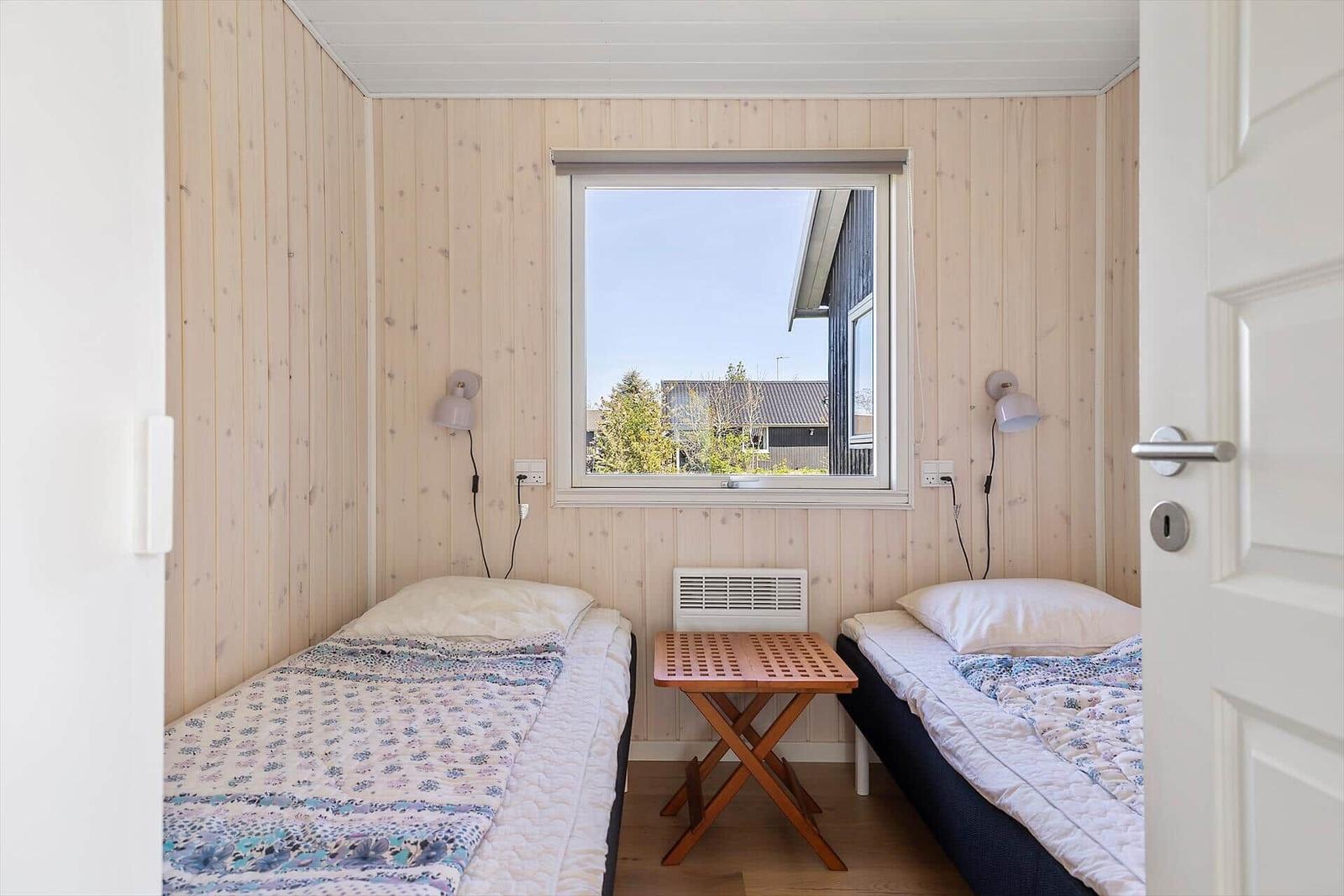 Zwei Einzelbetten mit Tisch und Fenster im Schlafzimmer.