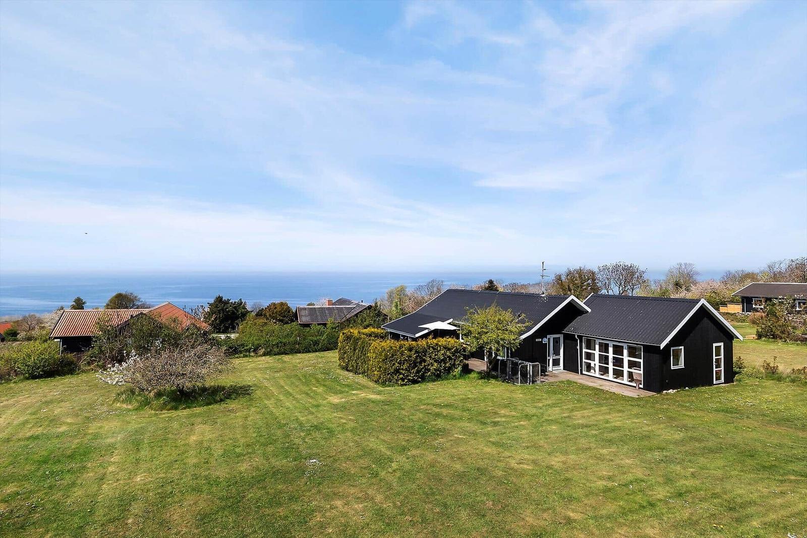 Schwarzes Haus mit Garten und Meerblick. Grünflächen und Bäume umgeben die Unterkunft.