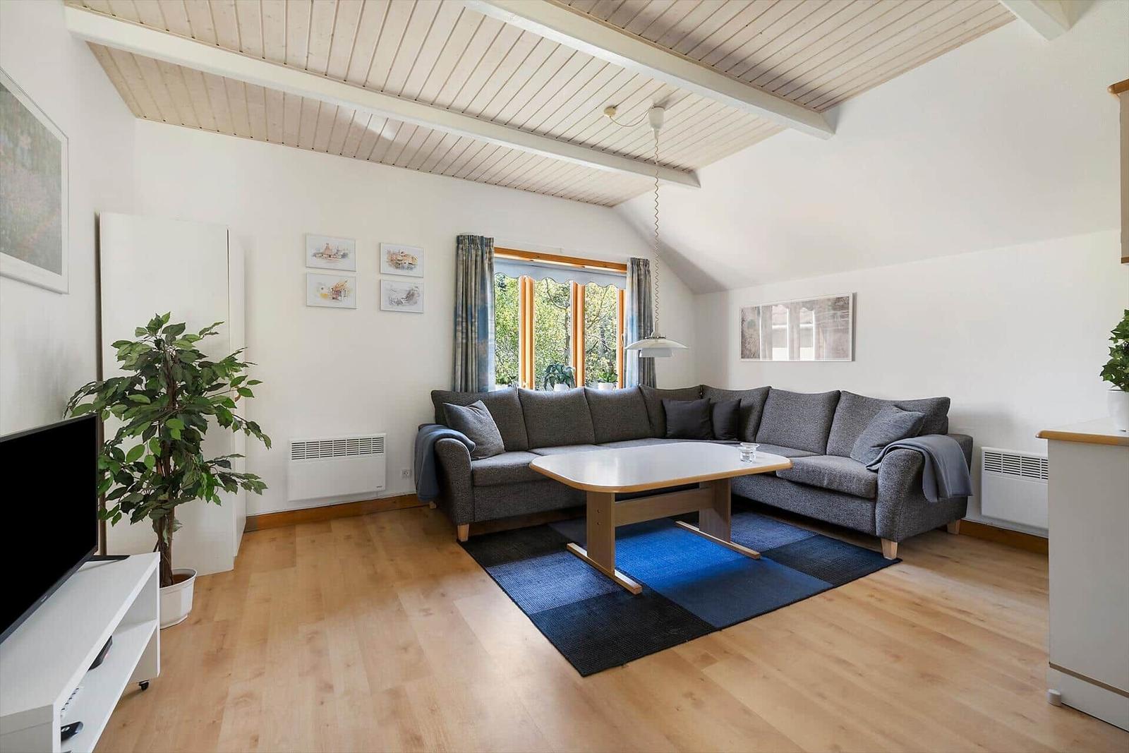 Wohnzimmer mit grauem Sofa, Holzboden und Dachschrägen.