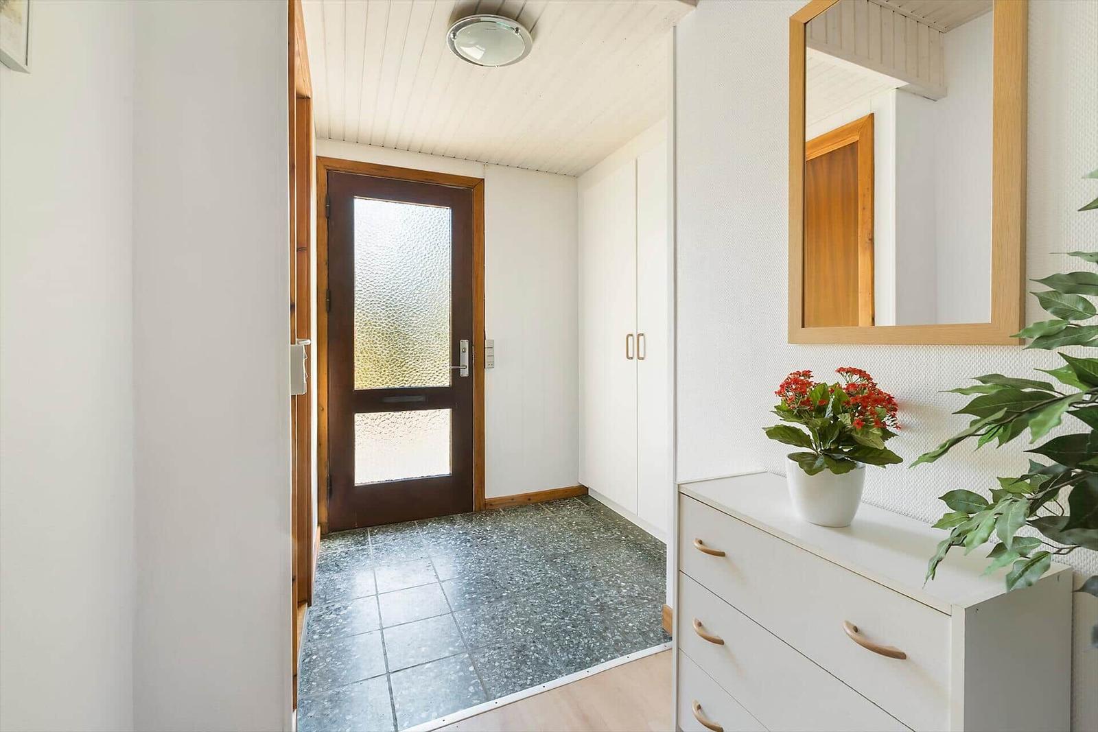 Eingangsbereich mit Holztür, Schrank und Schminktisch mit Spiegel.