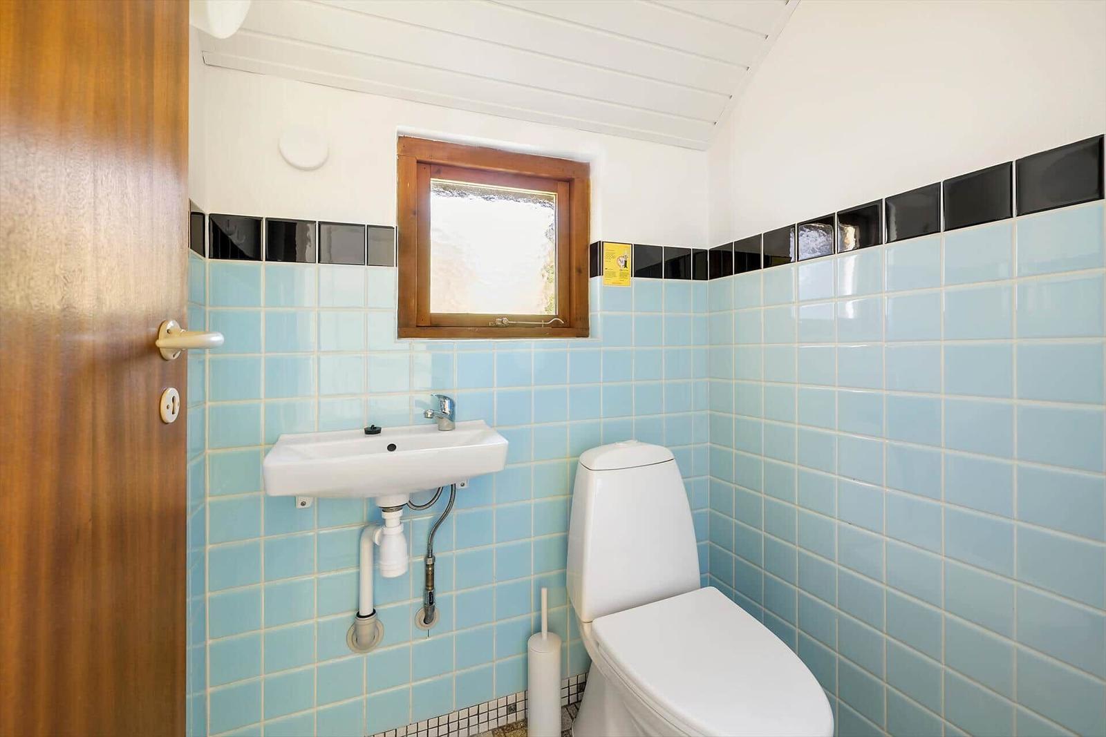Badezimmer mit Toilette, Waschbecken und Fenster