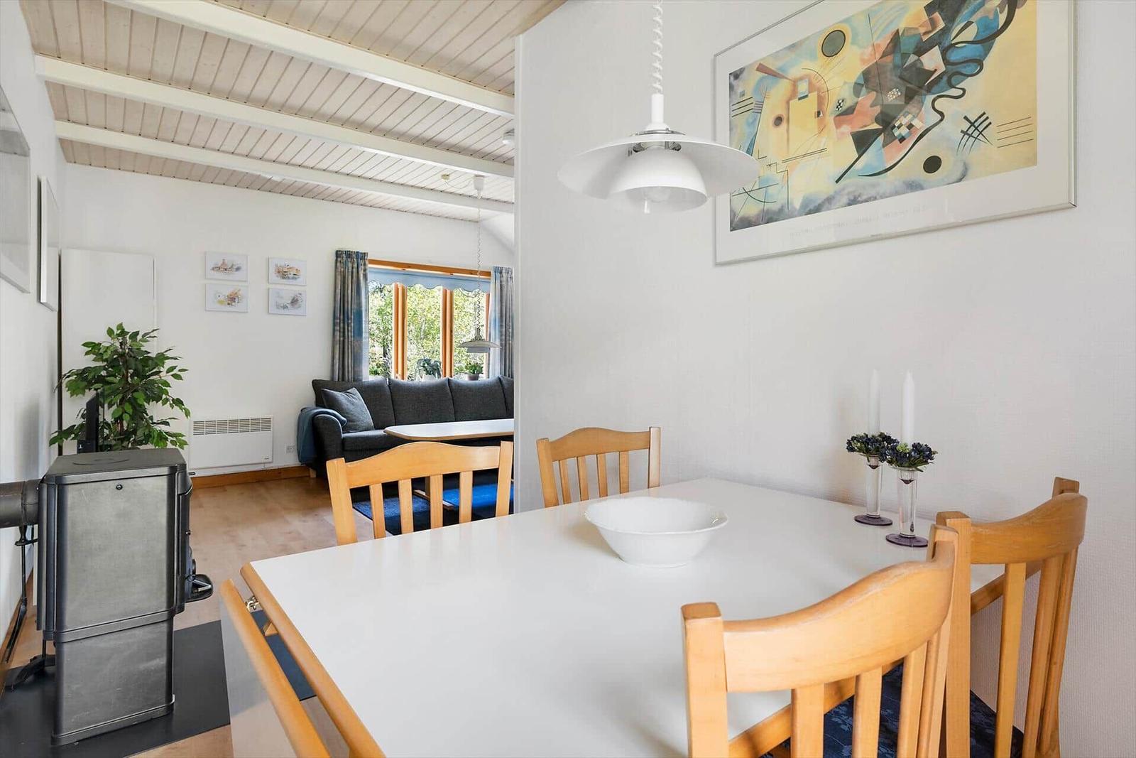 Esszimmer mit Tisch und Stühlen. Im Hintergrund Wohnbereich mit Sofa und Fenster.