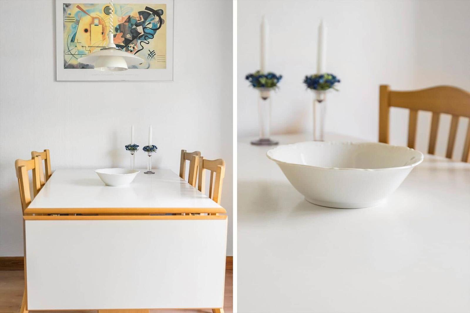 Esszimmer mit weißem Tisch, Holzstühlen und einer weißen Schale.