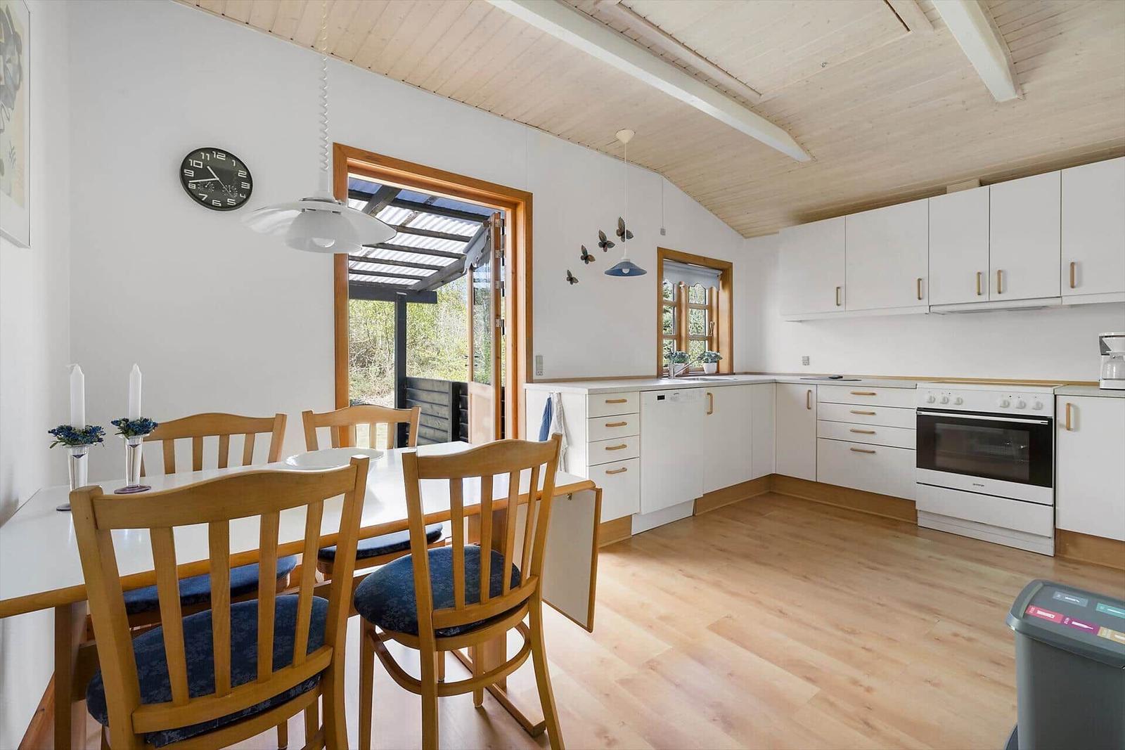 Küche und Essbereich mit Holzboden, weißen Schränken und Tisch mit Stühlen.