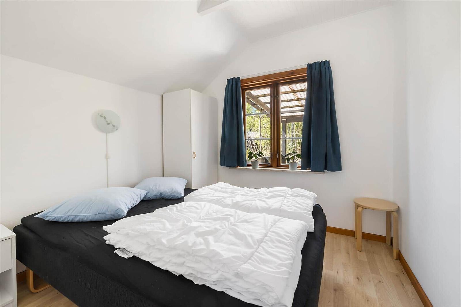 Schlafzimmer mit Bett, Fenster und Kleiderschrank.