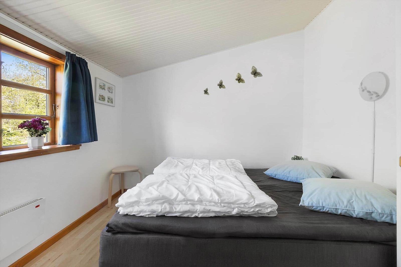 Schlafzimmer mit Bett, Fenster und Wanddekoration.