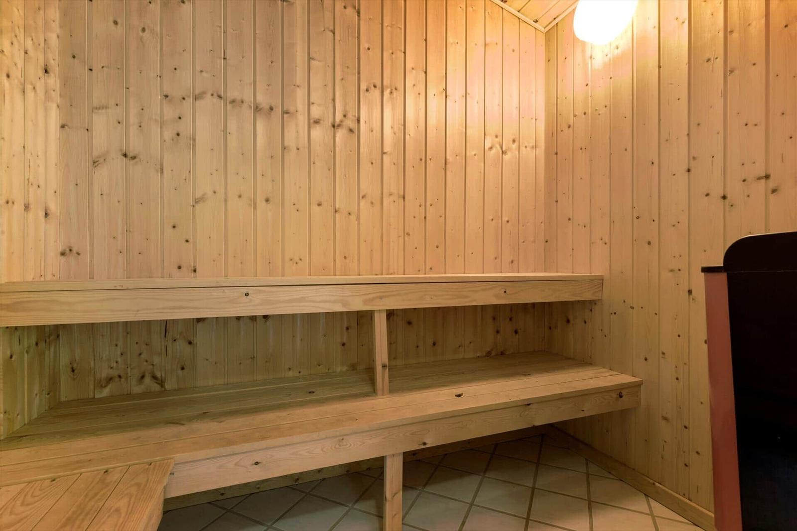 Sauna mit Holzwand und Sitzbänken auf Fliesenboden