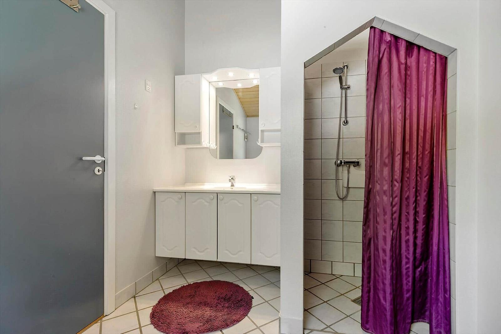 Badezimmer mit Dusche, Waschbecken und Spiegel