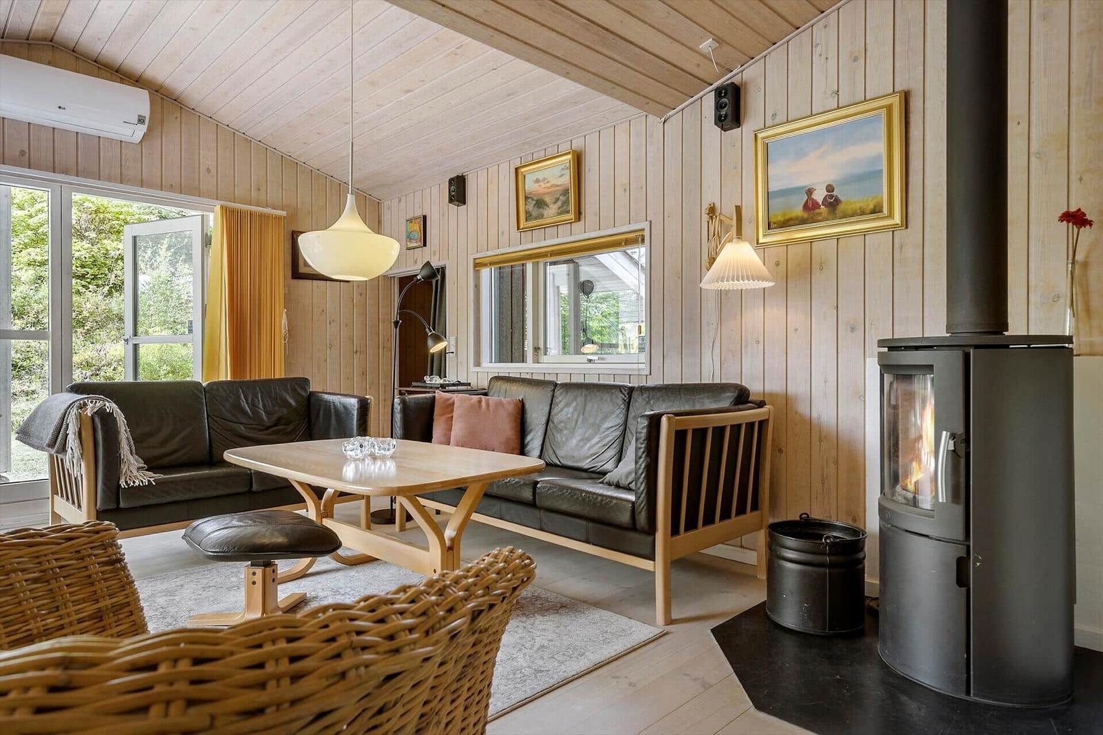 Wohnzimmer mit Holzwand, Sofa, Kamin und Tisch