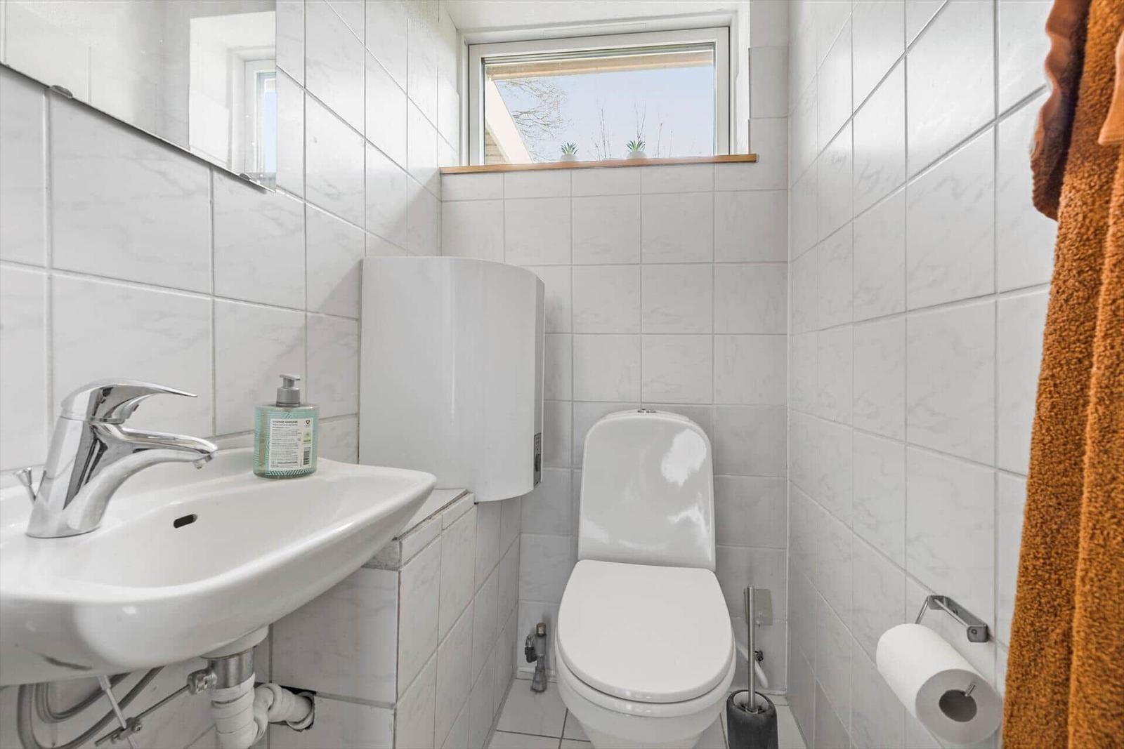 Bathroom with toilet, sink, and small window.