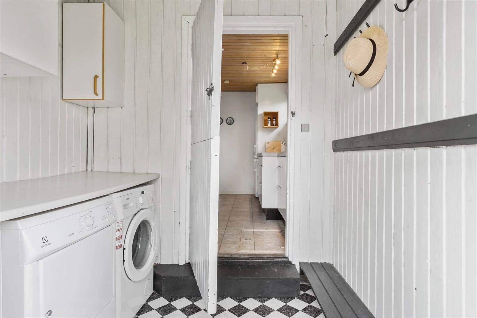 Apartment with washing machine, shoe rack, and view into the kitchen.