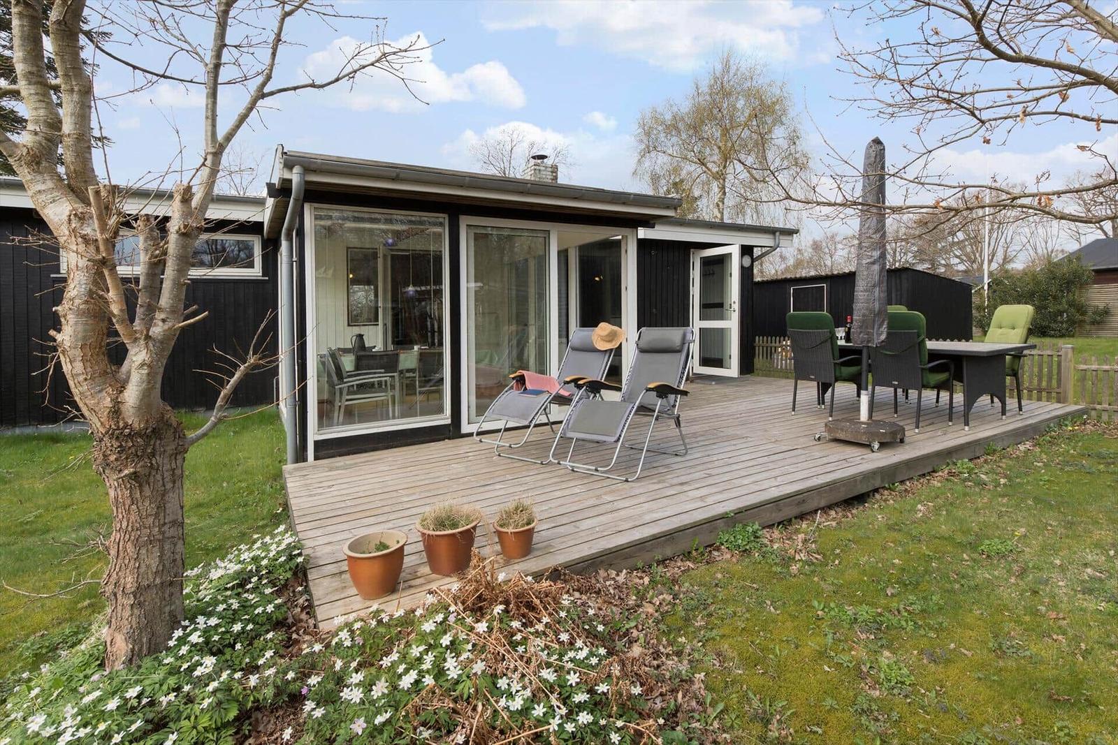 Modern vacation home with terrace, sun loungers, and garden.