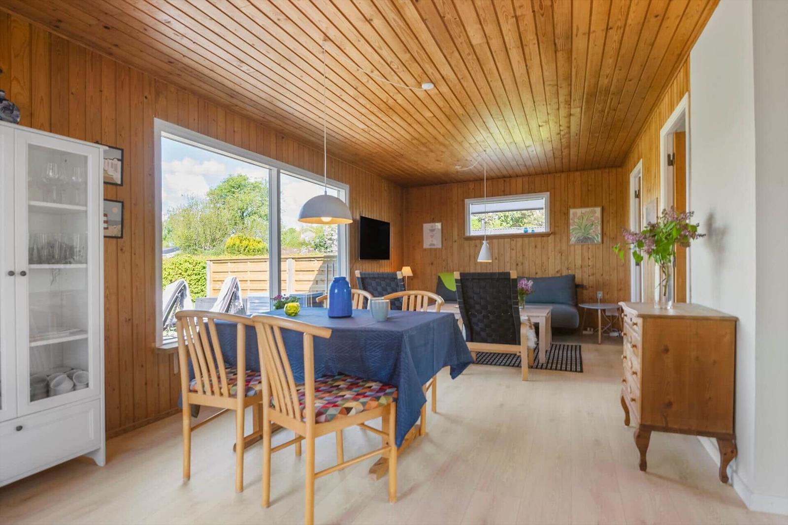 Essbereich mit Tisch, Stühlen und Blick auf Garten. Wohnbereich mit Sofa und Fernseher.