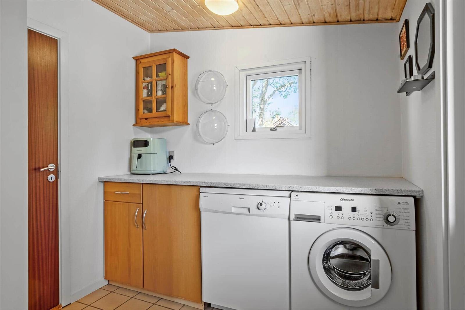 Wohnung mit Waschmaschine und Spülmaschine, Holzdecke und Fenster.
