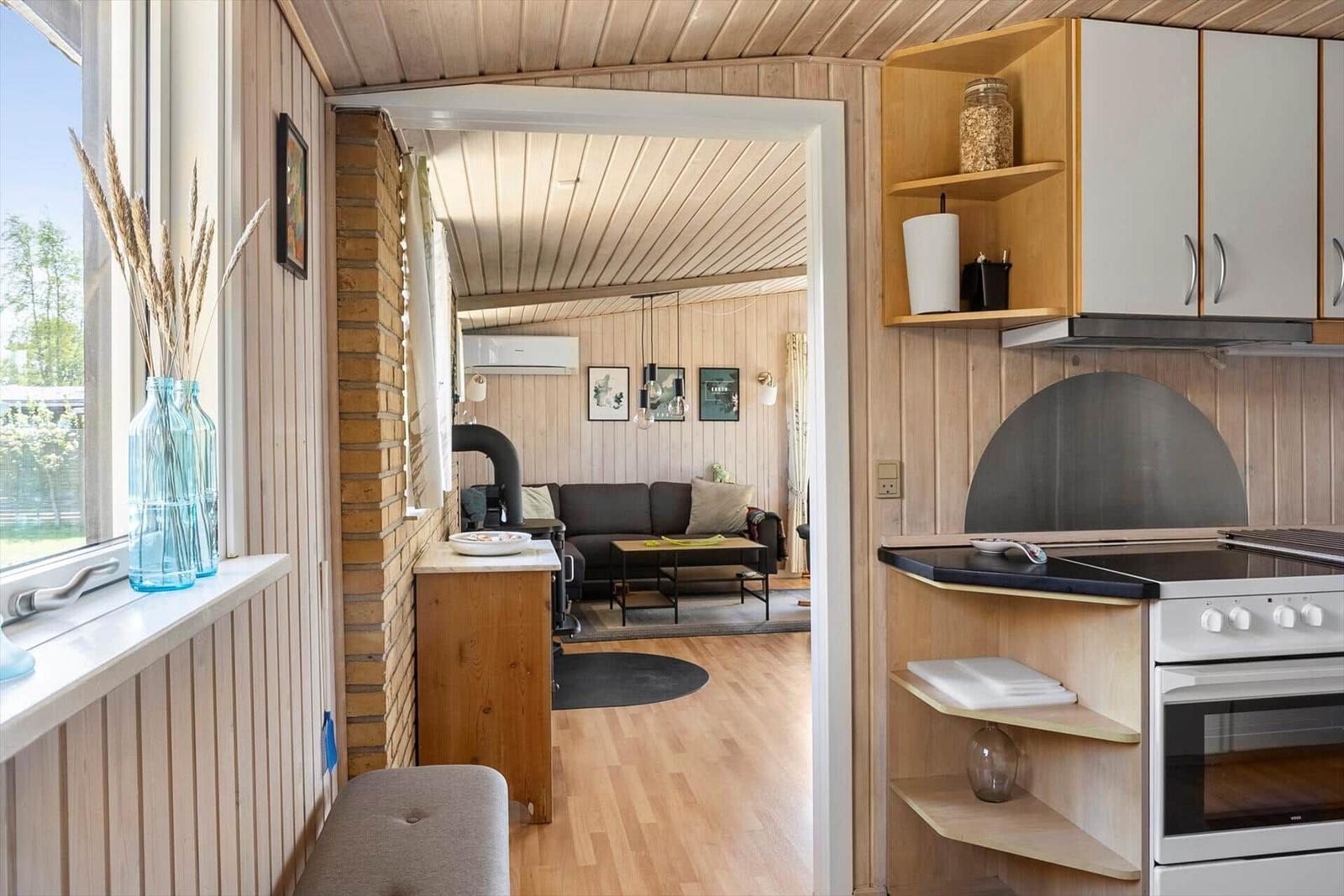 Küche mit Holzwand und Blick in Wohnzimmer mit Sofa und Kamin.